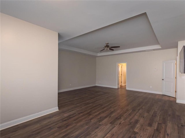 unfurnished room with dark wood-type flooring, ceiling fan, and a tray ceiling