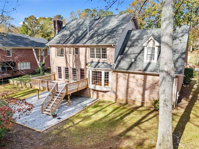 rear view of property featuring a lawn and a deck