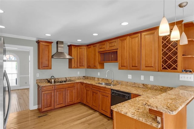 kitchen with sink, wall chimney exhaust hood, hanging light fixtures, light hardwood / wood-style flooring, and kitchen peninsula