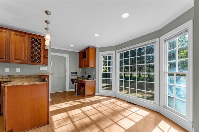 kitchen featuring pendant lighting, light hardwood / wood-style floors, light stone counters, and ornamental molding