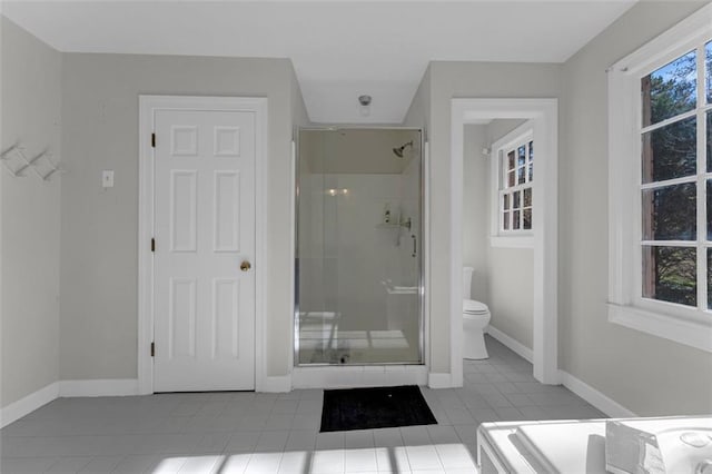 bathroom featuring tile patterned flooring, a shower with door, and toilet