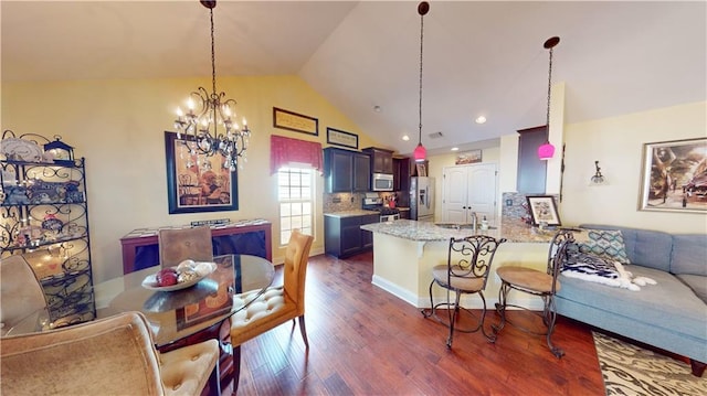 kitchen with pendant lighting, lofted ceiling, a breakfast bar, stainless steel appliances, and kitchen peninsula