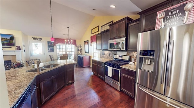 kitchen with lofted ceiling, sink, hanging light fixtures, appliances with stainless steel finishes, and backsplash