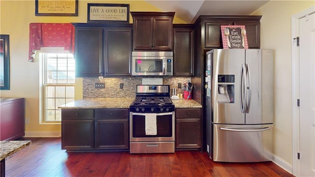 kitchen with lofted ceiling, stainless steel appliances, light stone countertops, and decorative backsplash