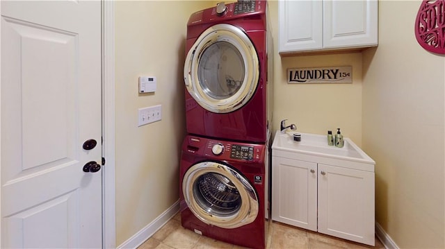 laundry area with stacked washer and dryer, cabinets, and light tile patterned flooring