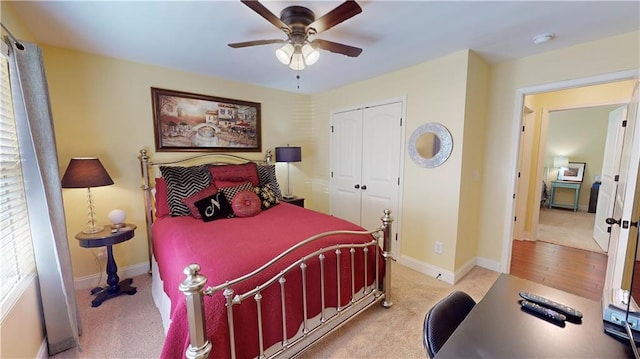 bedroom with ceiling fan, light carpet, and a closet