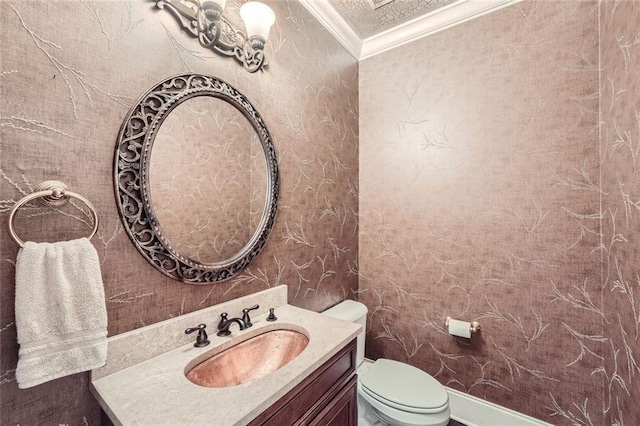 bathroom with toilet, ornamental molding, and vanity