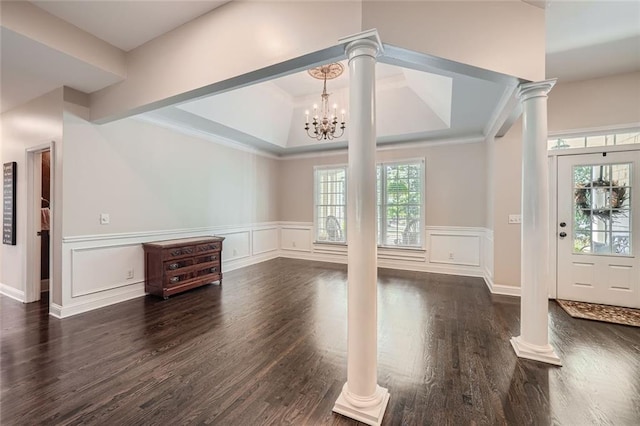 foyer with dark wood finished floors, a decorative wall, and decorative columns