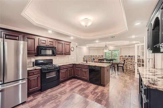 kitchen featuring backsplash, a tray ceiling, a peninsula, black appliances, and a sink