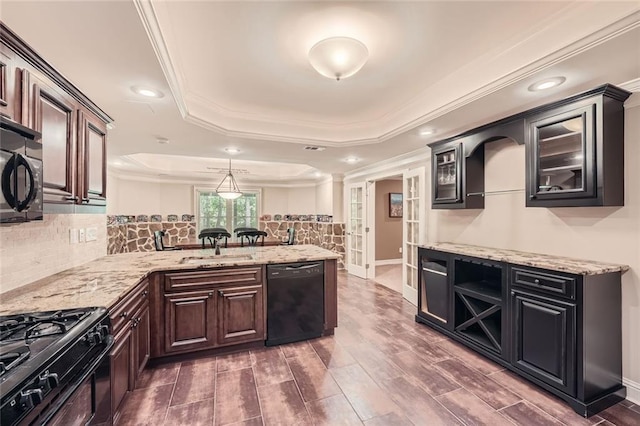 kitchen with glass insert cabinets, a tray ceiling, ornamental molding, a peninsula, and black appliances