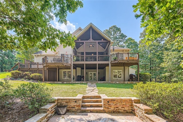 rear view of property with french doors, a wooden deck, a yard, and a sunroom