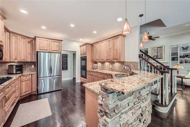 kitchen featuring light brown cabinetry, a sink, freestanding refrigerator, a peninsula, and light stone countertops