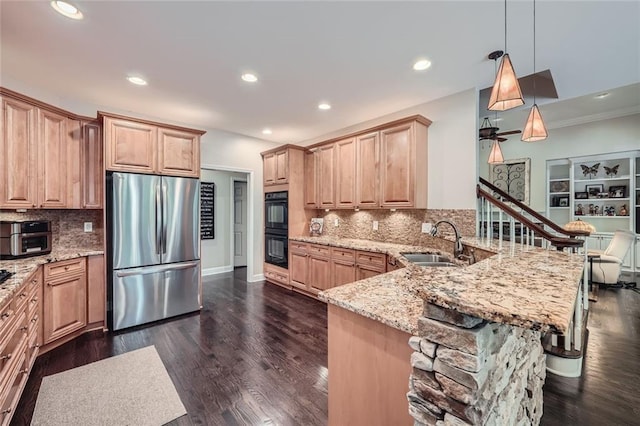 kitchen featuring dobule oven black, a sink, light stone counters, freestanding refrigerator, and a peninsula