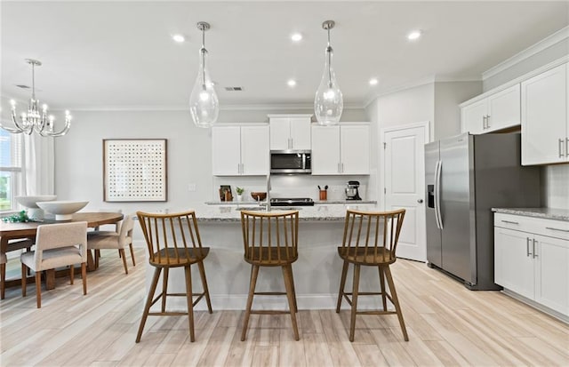 kitchen featuring a center island with sink, appliances with stainless steel finishes, white cabinetry, and light stone counters