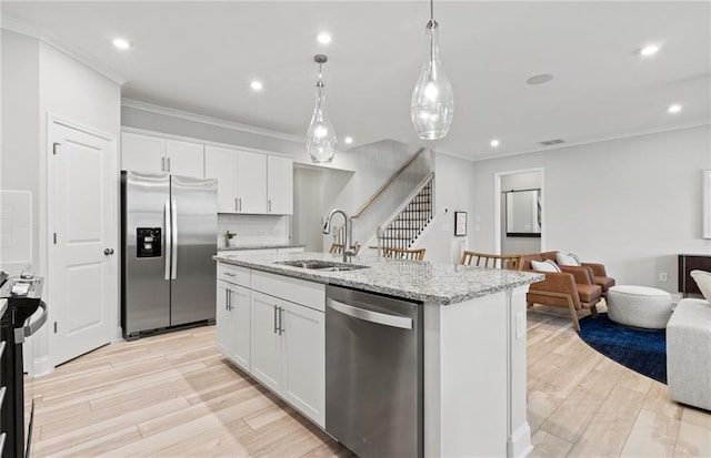 kitchen with sink, hanging light fixtures, a kitchen island with sink, appliances with stainless steel finishes, and white cabinets