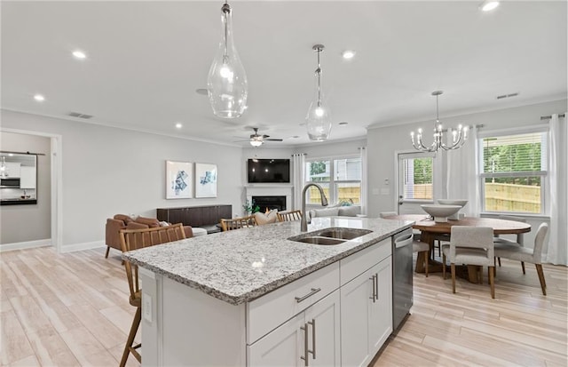 kitchen featuring ceiling fan with notable chandelier, sink, white cabinets, and an island with sink