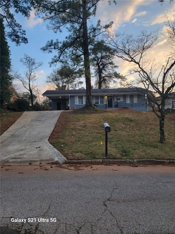 view of front facade featuring driveway, a lawn, and a carport