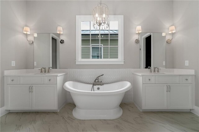 bathroom with an inviting chandelier, vanity, and a bath