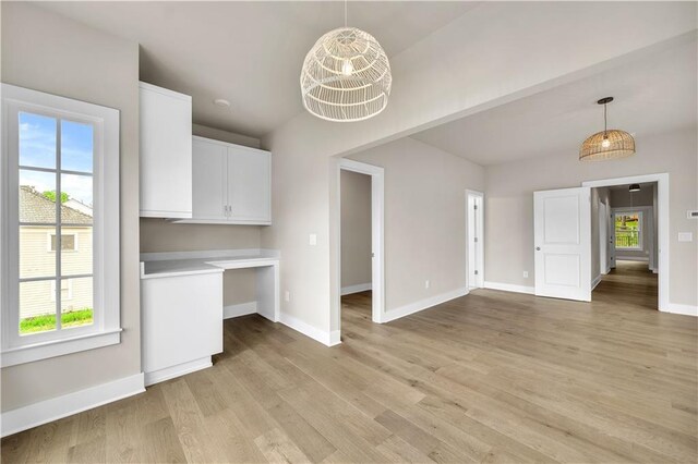 interior space featuring light hardwood / wood-style flooring, hanging light fixtures, a healthy amount of sunlight, and white cabinets