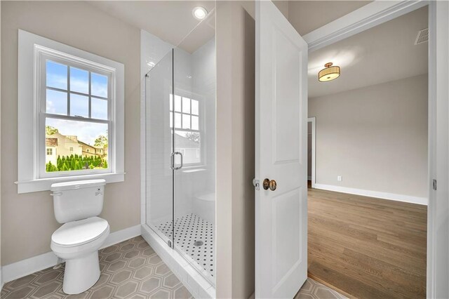 bathroom with hardwood / wood-style flooring, toilet, and walk in shower