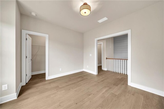 unfurnished bedroom with light hardwood / wood-style floors, a closet, and a spacious closet