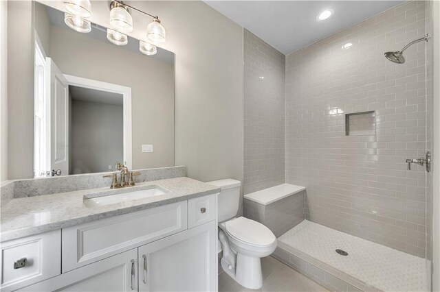 bathroom with toilet, vanity, tile patterned floors, and tiled shower