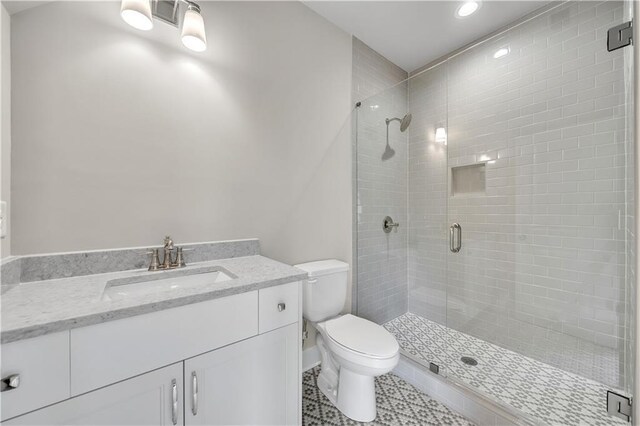 bathroom featuring toilet, an enclosed shower, vanity, and tile patterned floors