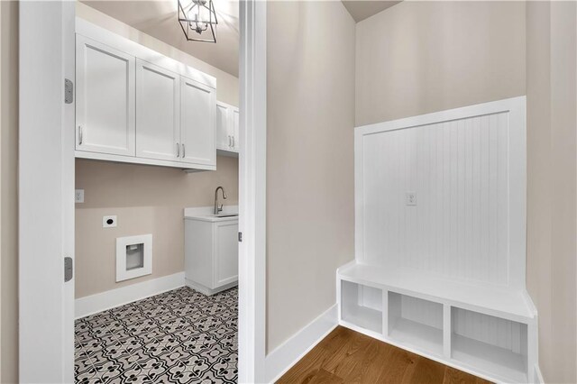 clothes washing area featuring electric dryer hookup, light hardwood / wood-style flooring, sink, cabinets, and a chandelier