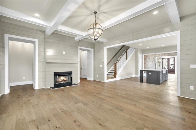 unfurnished living room featuring light hardwood / wood-style floors, wood walls, and beamed ceiling