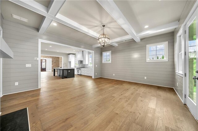 unfurnished living room featuring light hardwood / wood-style flooring, wood walls, and plenty of natural light