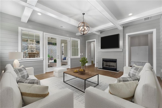 living room with beam ceiling, a chandelier, a fireplace, and light hardwood / wood-style floors