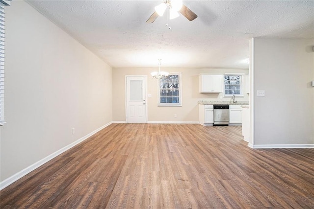 unfurnished living room featuring wood-type flooring, ceiling fan with notable chandelier, and a textured ceiling