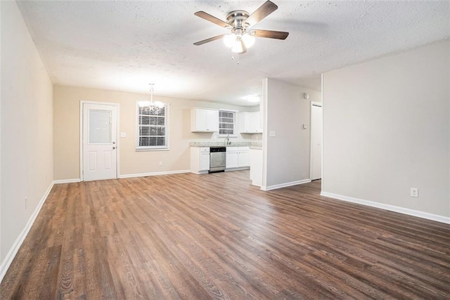 unfurnished living room featuring dark hardwood / wood-style floors, ceiling fan with notable chandelier, and a textured ceiling