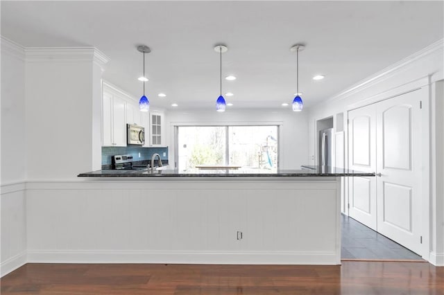 kitchen with glass insert cabinets, dark wood finished floors, appliances with stainless steel finishes, a peninsula, and white cabinetry