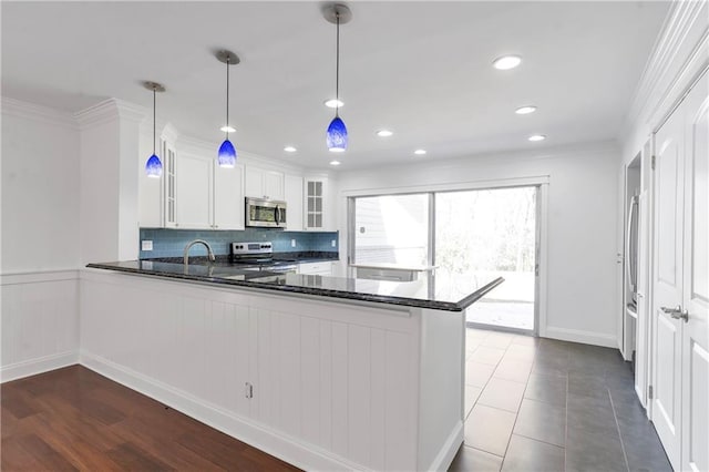 kitchen with a peninsula, stainless steel appliances, glass insert cabinets, white cabinetry, and backsplash