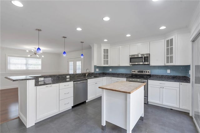 kitchen featuring a peninsula, white cabinets, plenty of natural light, and stainless steel appliances