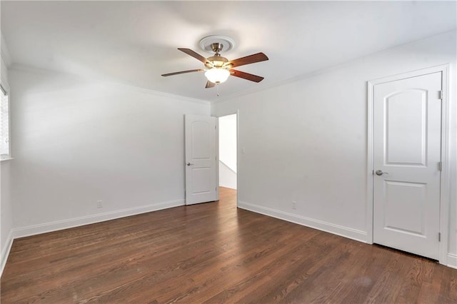 spare room featuring baseboards, dark wood-type flooring, ornamental molding, and a ceiling fan