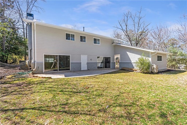 back of property with brick siding, a lawn, and a patio area