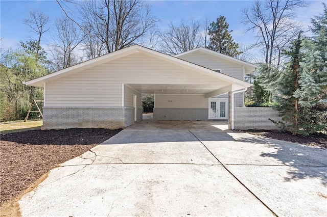 view of home's exterior with brick siding, french doors, concrete driveway, and a carport