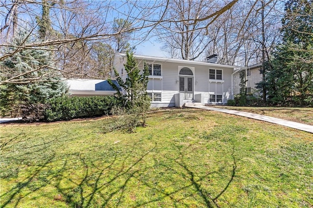 view of front of home with entry steps, a front yard, and a chimney