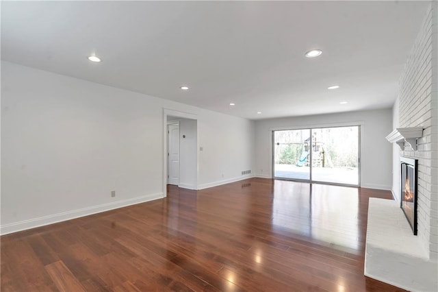 unfurnished living room with recessed lighting, baseboards, a brick fireplace, and wood finished floors