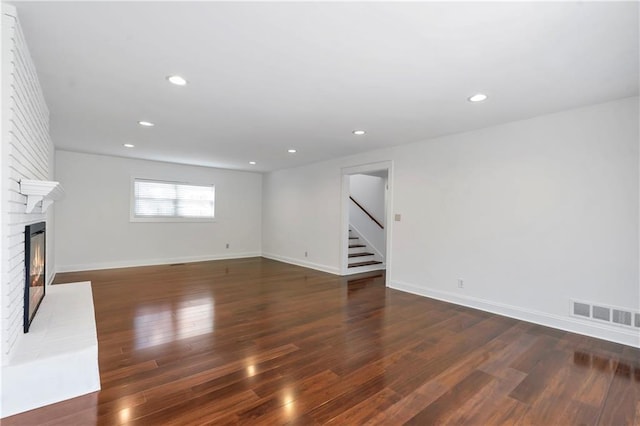 unfurnished living room with stairway, wood finished floors, visible vents, recessed lighting, and a fireplace