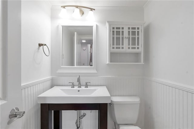 bathroom featuring a wainscoted wall, toilet, ornamental molding, and vanity