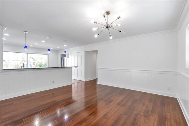 unfurnished living room featuring a wainscoted wall, hardwood / wood-style floors, recessed lighting, an inviting chandelier, and crown molding