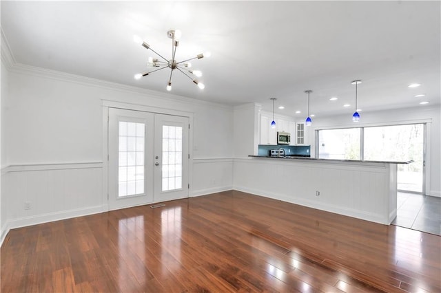 unfurnished living room with crown molding, french doors, dark wood-style flooring, and a wealth of natural light