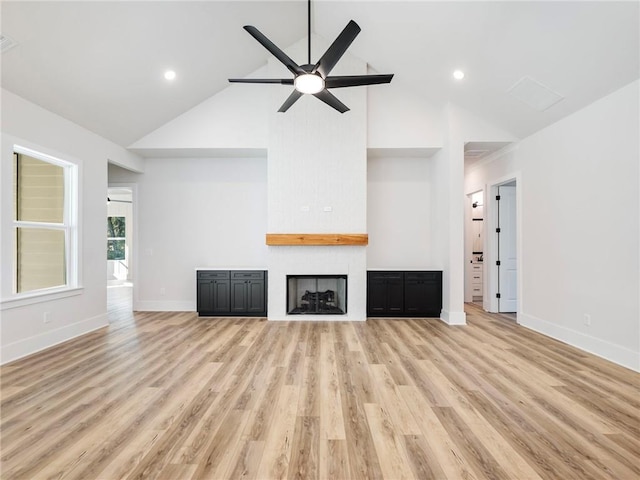 unfurnished living room featuring a large fireplace, high vaulted ceiling, light hardwood / wood-style floors, and ceiling fan