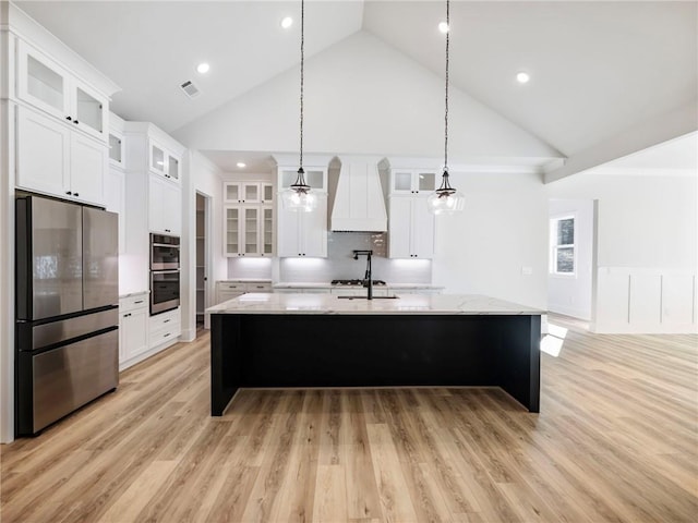 kitchen featuring stainless steel appliances, white cabinetry, custom exhaust hood, and light hardwood / wood-style flooring