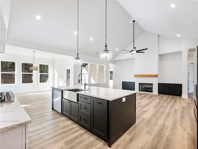 kitchen with light hardwood / wood-style floors, sink, high vaulted ceiling, a fireplace, and pendant lighting