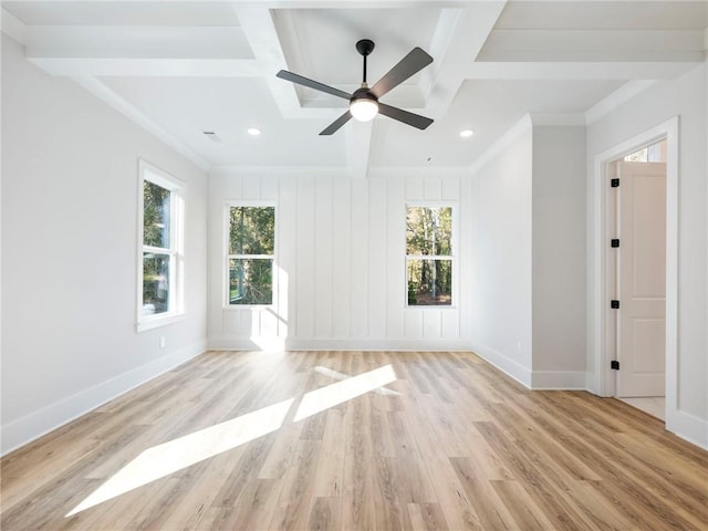 empty room with beamed ceiling, a wealth of natural light, ceiling fan, and light hardwood / wood-style flooring