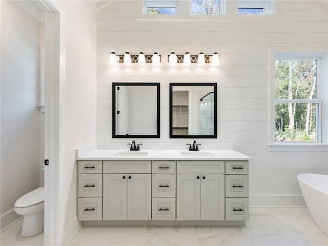 bathroom featuring toilet, wood walls, a washtub, and vanity